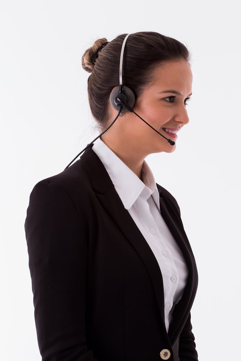 Photo by Michael Wysmierski Cheerful call center agent wearing a headset and black blazer, ready to assist customers.