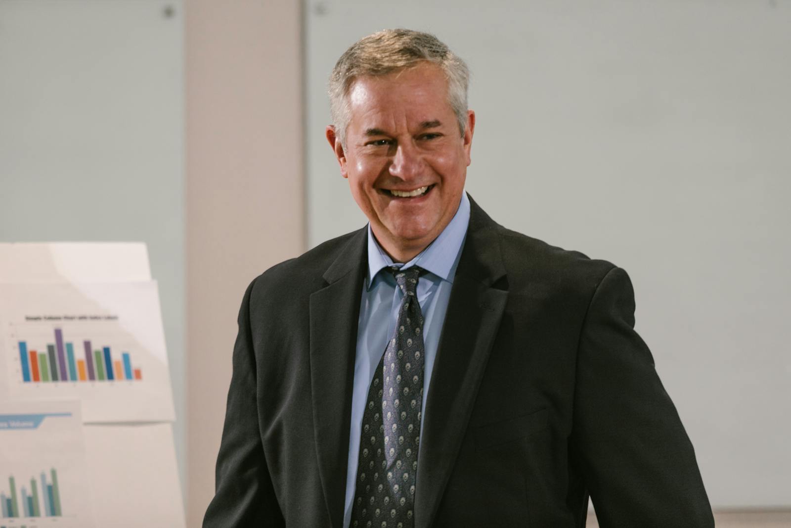 Photo by RDNE Stock project Smiling businessman in a corporate setting with charts. Professional and confident.