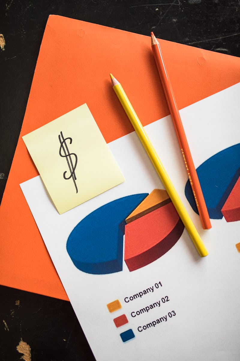 Close-up of pie chart and notes with colorful pencils on wood desk, ideal for business presentations.