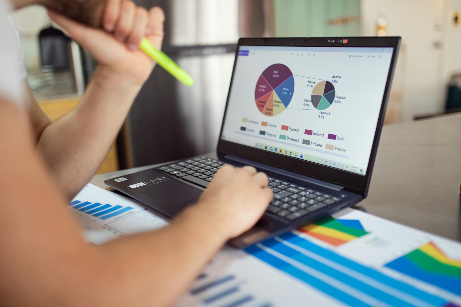 Photo by RDNE Stock project Person analyzing financial charts and graphs on a laptop with colorful documents, showcasing market analysis.