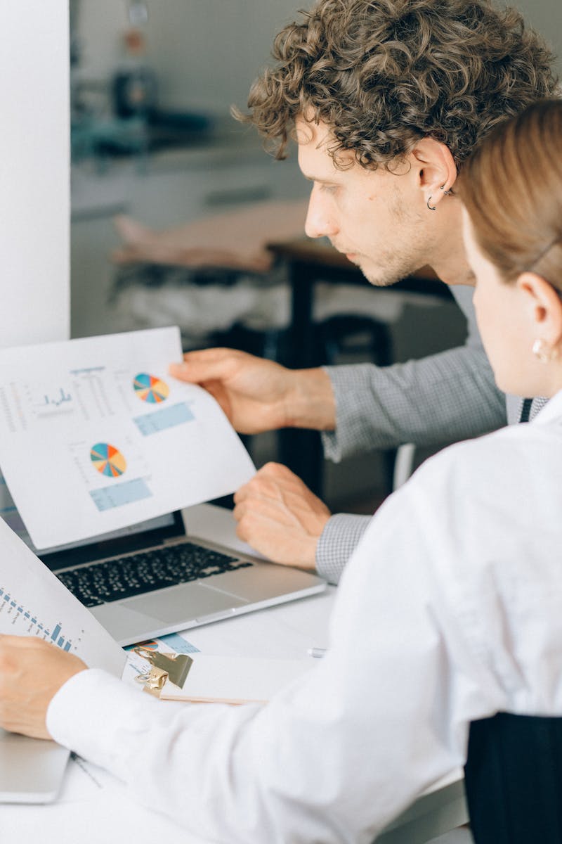 Photo by Nataliya Vaitkevich Two business professionals reviewing financial charts and graphs in a modern office setting.