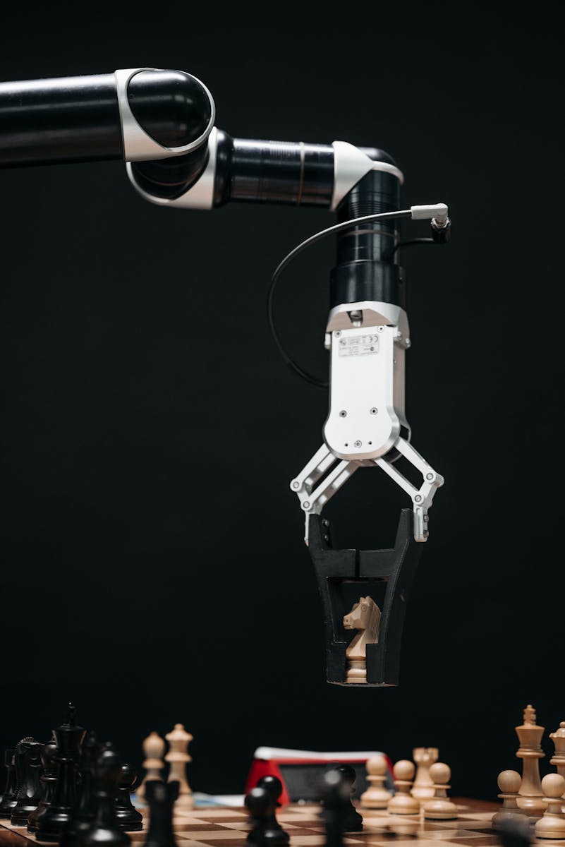 Photo by Pavel Danilyuk A robotic arm with a pincers holding a knight chess piece on a chessboard.