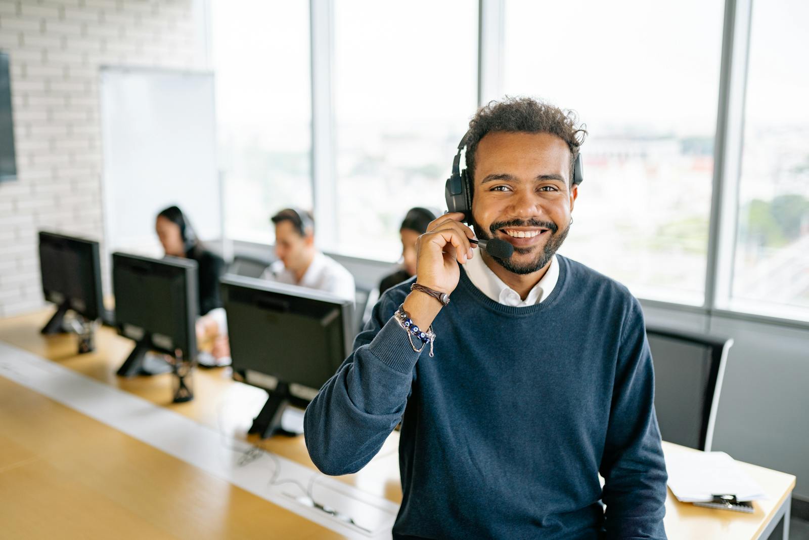 Photo by Yan Krukau Cheerful male call center agent with headset in a bright office environment.