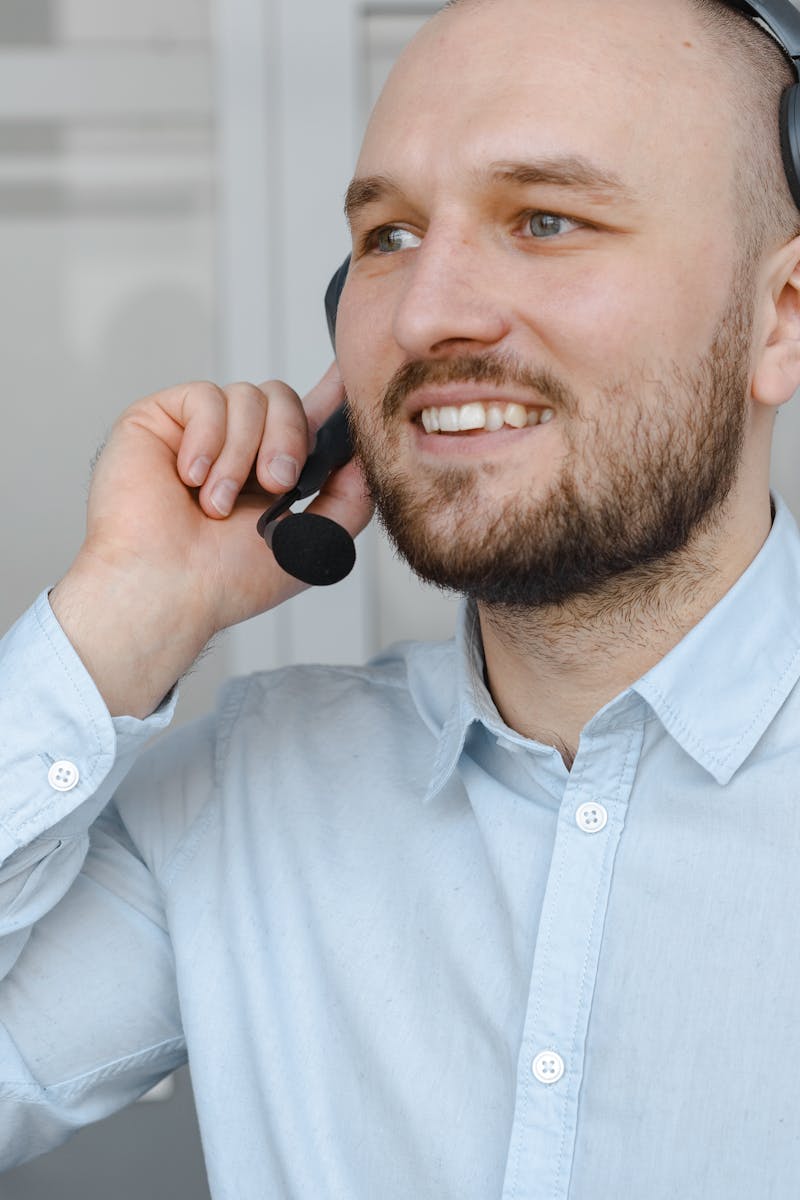 Photo by Mikhail Nilov Smiling man with headset providing customer service support on a call.
