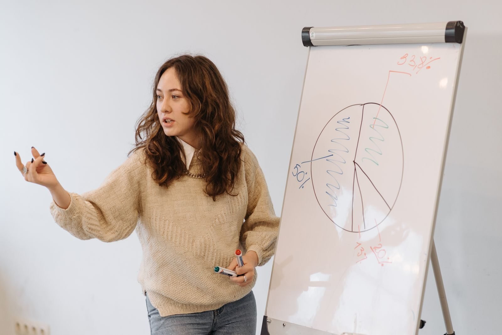 Woman gives presentation with pie chart on whiteboard, explaining data analysis.